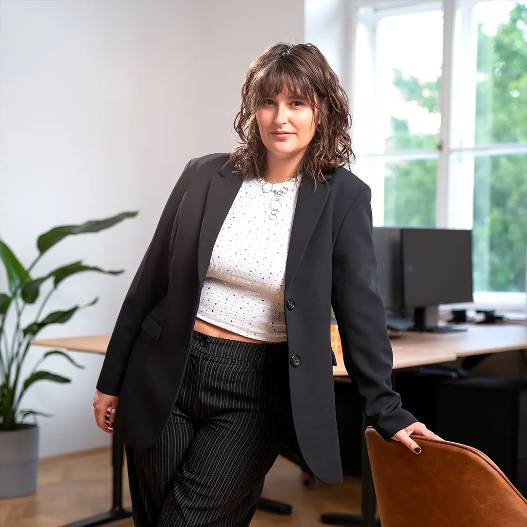 Romy, Art Director at OSTWERK, leaning on a desk in the office
